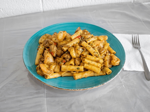 A vibrant teal plate holds a generous serving of pasta with shrimp and chicken, alongside a fork.