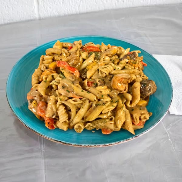 Creamy pasta with shrimp, mushrooms, and bell peppers on a blue plate with a fork.