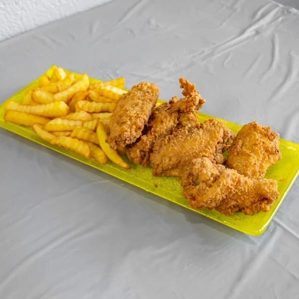 Crispy fried chicken tenders and crinkle-cut french fries on a bright green rectangular plate.