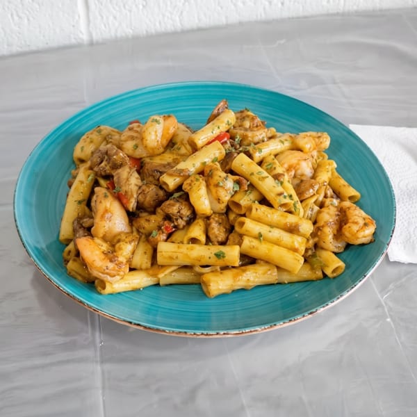 A vibrant teal plate holds a generous serving of pasta with shrimp and chicken, alongside a fork.