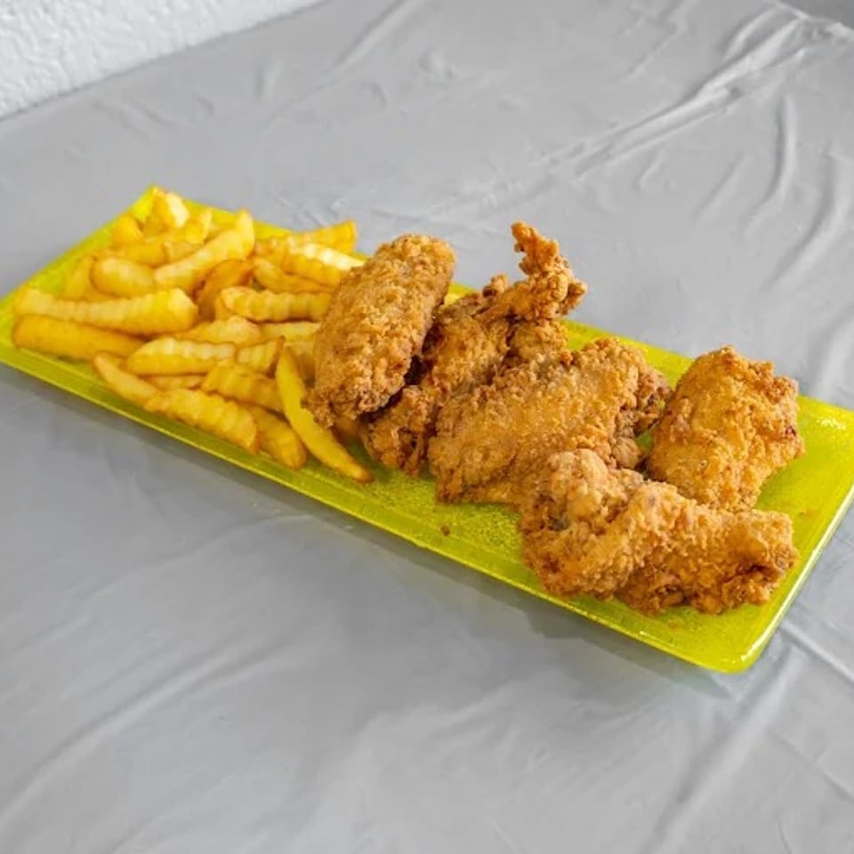 Golden fried chicken tenders and crinkle-cut fries on a bright green rectangular plate.
