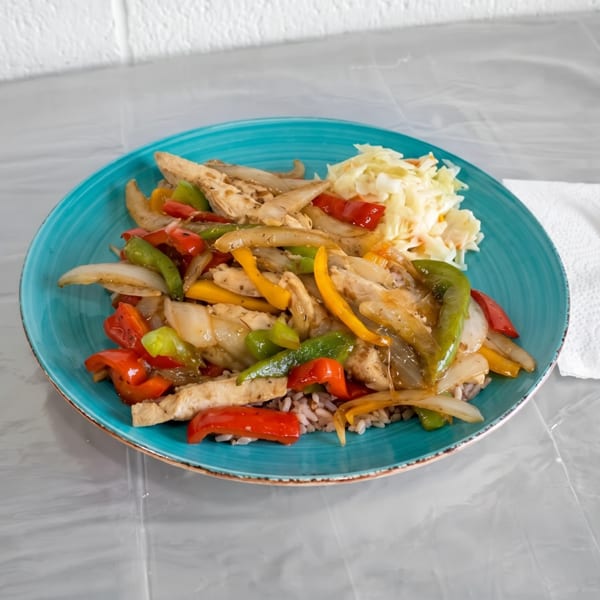 Chicken stir-fry with colorful bell peppers, onions, and rice, served with coleslaw on a blue plate.